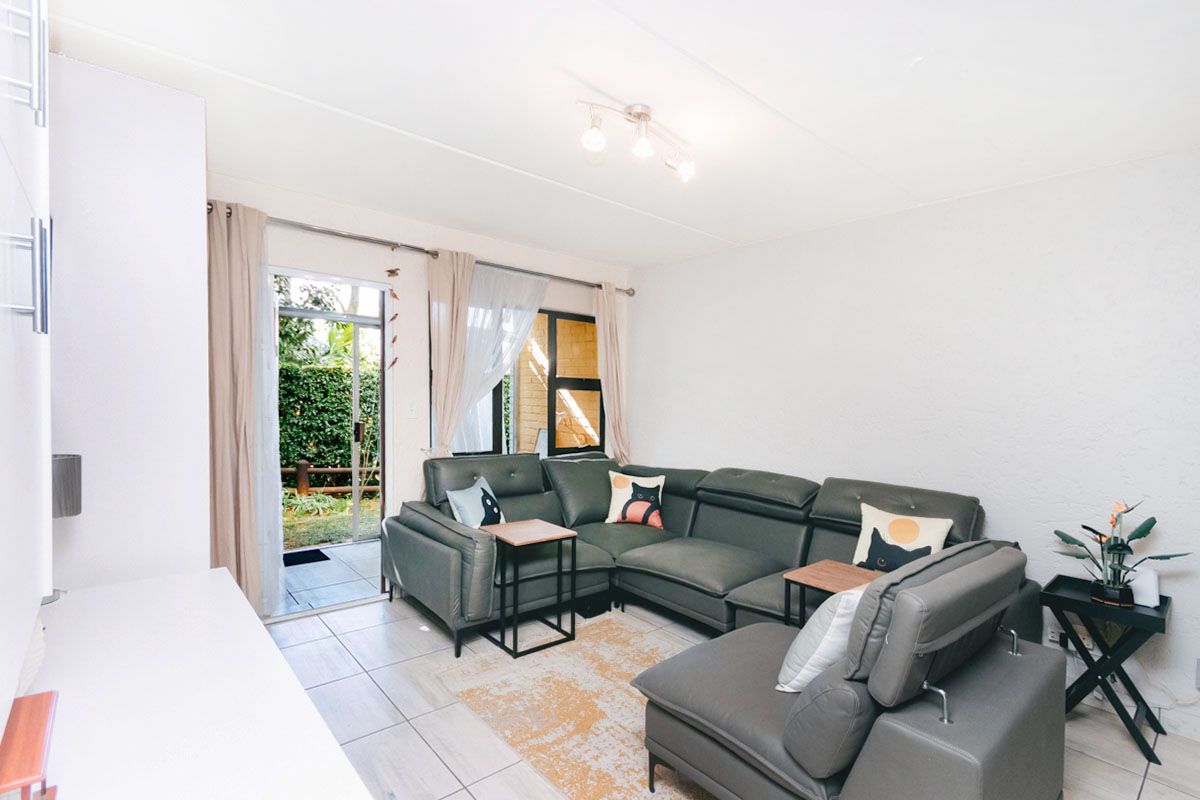 A bright living room featuring tiled flooring and a sliding glass door providing direct access to the outdoor area.