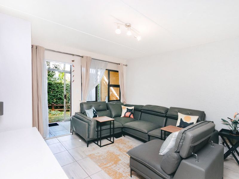 A bright living room featuring tiled flooring and a sliding glass door providing direct access to the outdoor area.