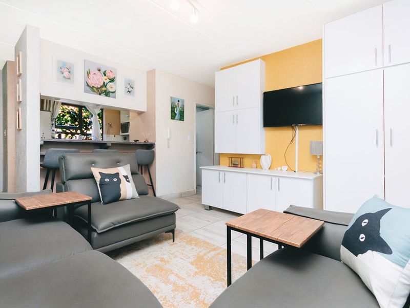 Open-plan living area featuring tiled flooring, built-in storage cabinetry, and a breakfast bar connecting to the kitchen space.