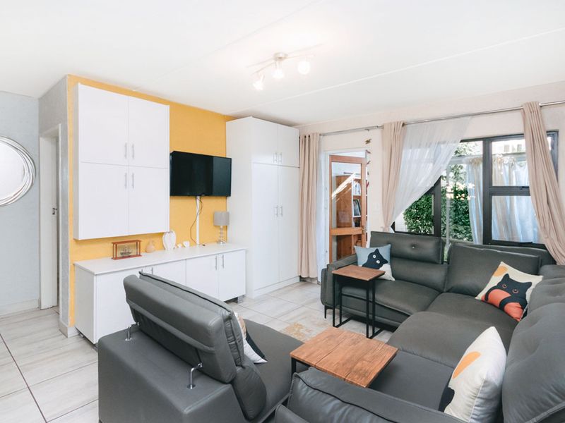 A bright living room featuring built-in white cabinetry, tiled flooring, and a sliding glass door providing access to the outdoor area.