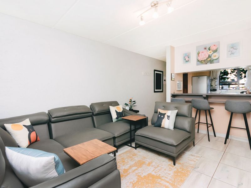 Open plan living area featuring tiled flooring, a breakfast bar counter, and modern track lighting, creating a functional and connected space.