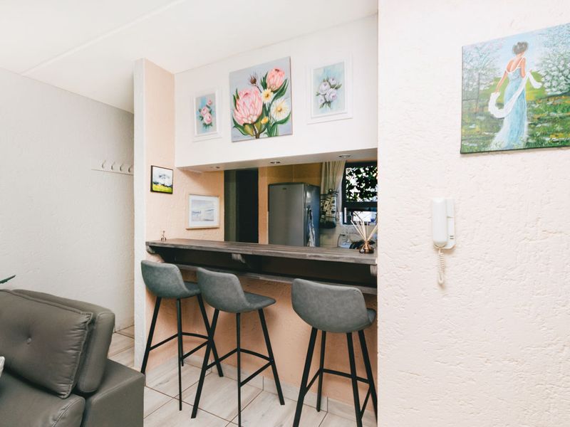 Open plan living area featuring a breakfast bar counter, tiled flooring, and an integrated intercom system, connecting to the kitchen space.