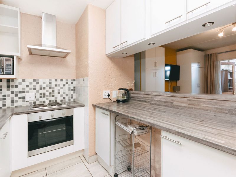 A functional kitchen featuring built-in cabinetry, a gas hob with extractor fan, oven, and laminate countertops with a tiled backsplash.