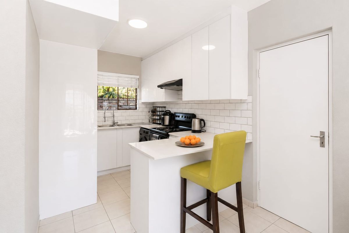 Modern kitchen featuring white cabinetry, subway tile backsplash, stone countertops, and a convenient breakfast bar for casual dining.