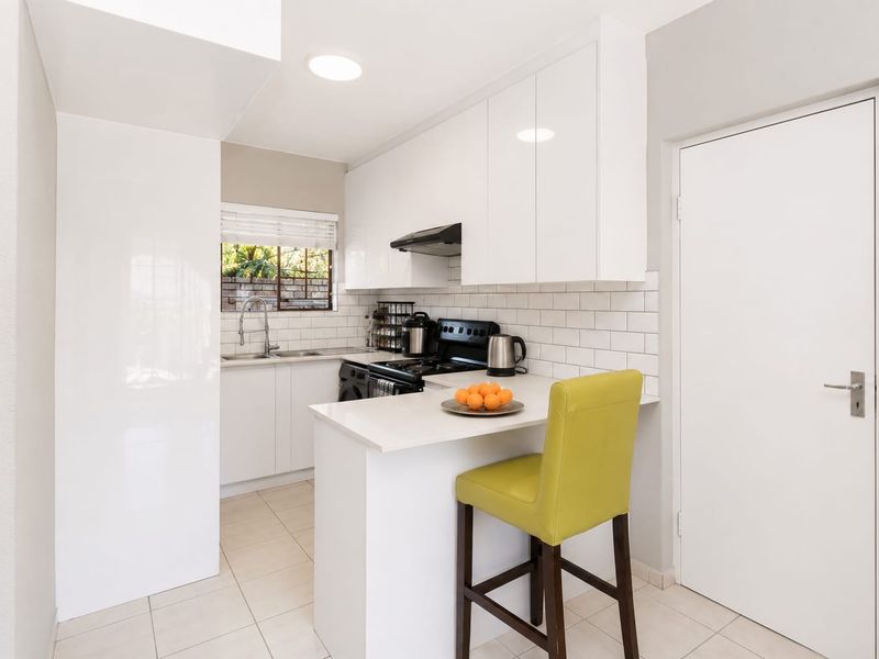 Modern kitchen featuring white cabinetry, subway tile backsplash, stone countertops, and a convenient breakfast bar for casual dining.