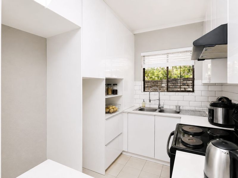 Modern kitchen featuring white gloss cabinetry, subway tile backsplash, double bowl stainless steel sink, and integrated extractor fan.