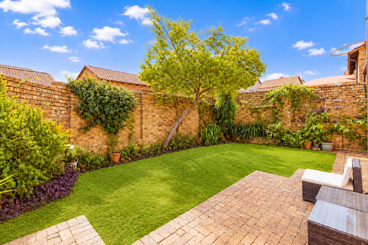 A private rear garden featuring a well-maintained lawn, paved patio area, and established brick boundary walls.