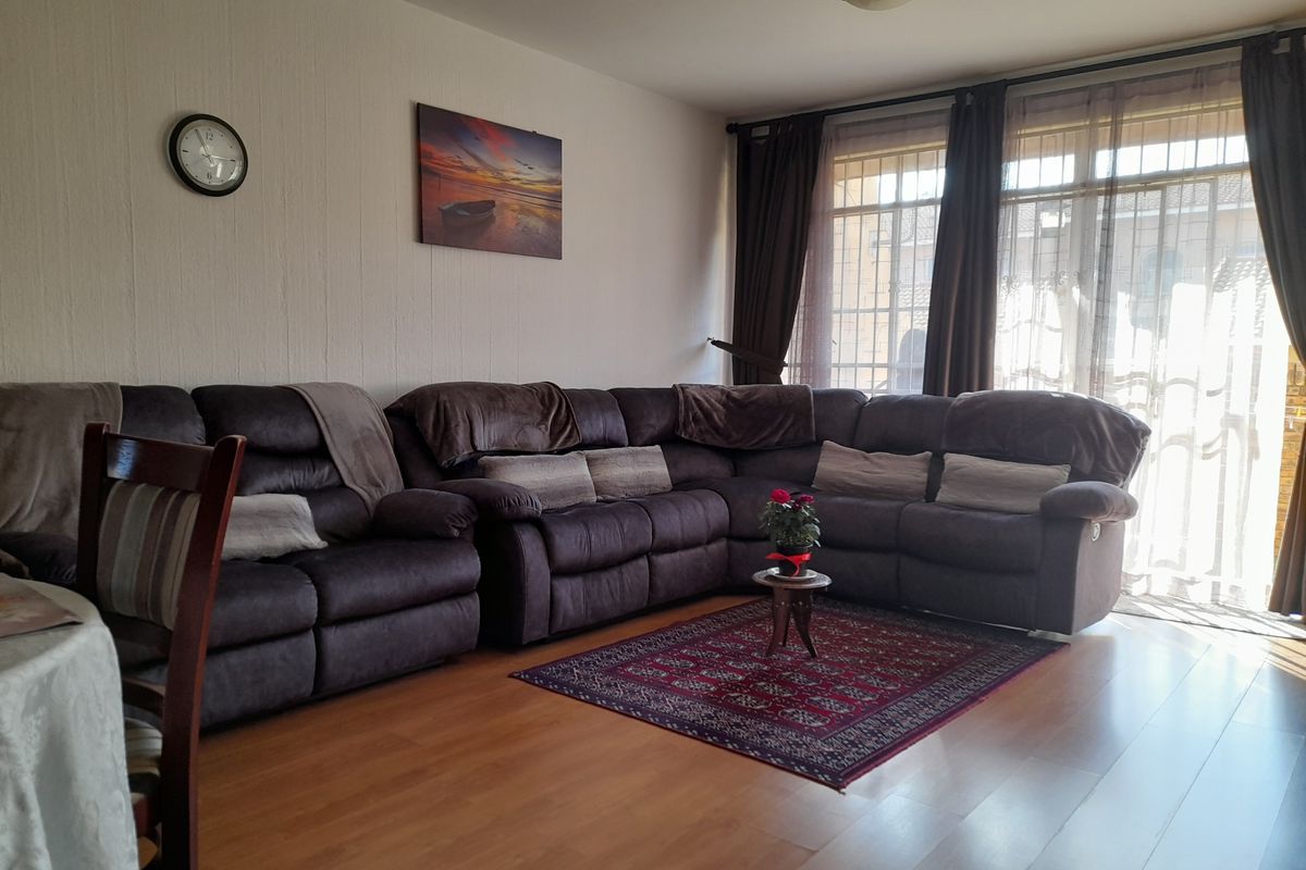 A comfortable living room featuring laminate flooring and large sliding glass doors that provide ample natural light.