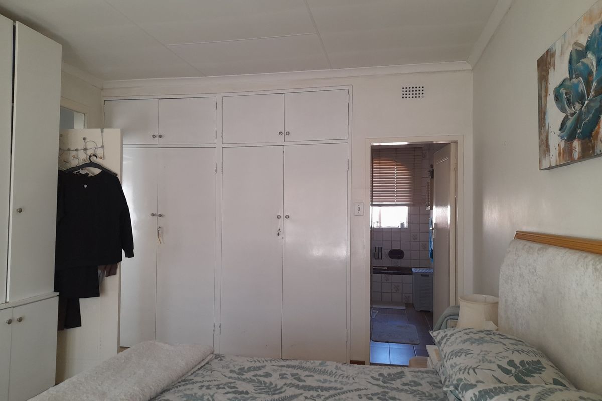 Bedroom featuring extensive built-in cupboards and direct access to an en-suite bathroom, offering functional storage space.