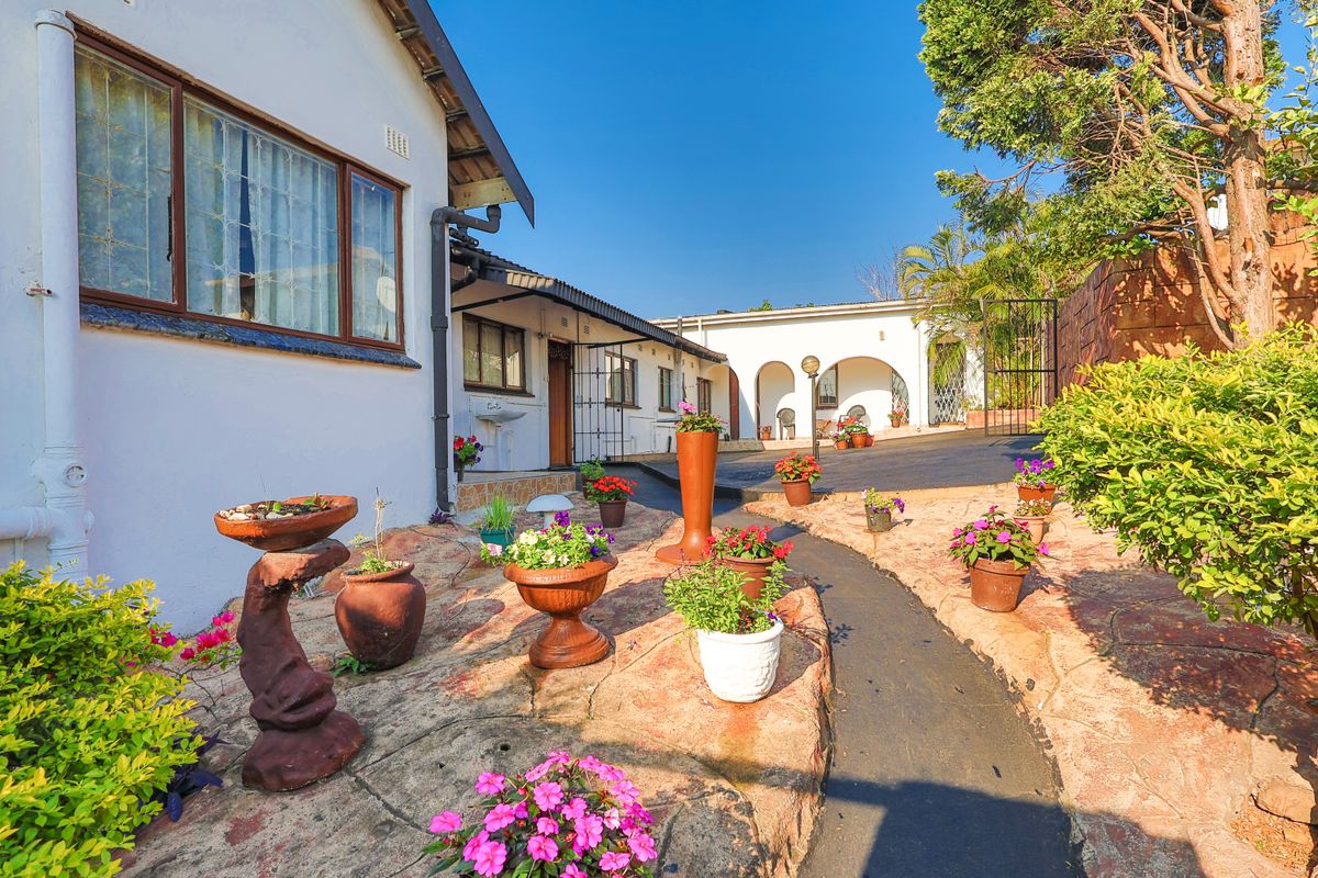 A rear courtyard area featuring a paved walkway, an external basin, and an arched covered patio entrance to the main house.