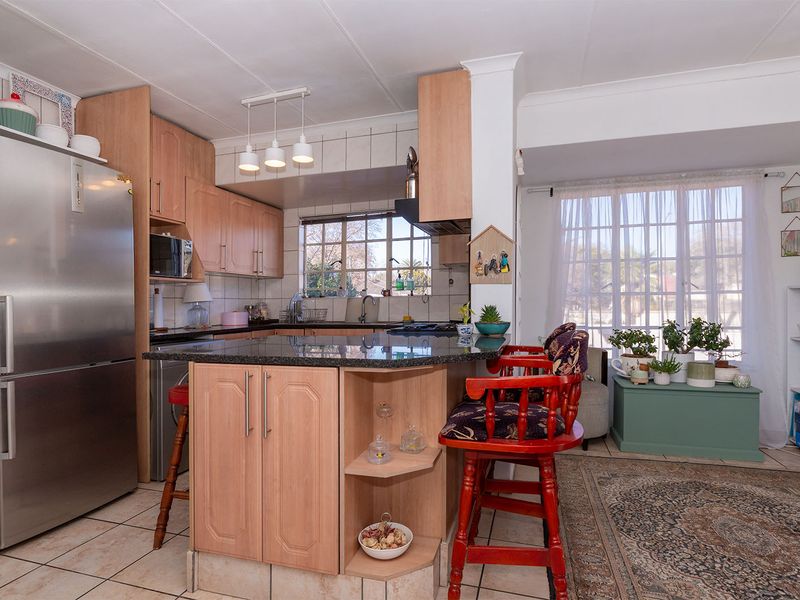 Open-plan kitchen featuring laminate cabinetry, granite countertops, and a breakfast nook, seamlessly flowing into the adjacent living area with natural light.