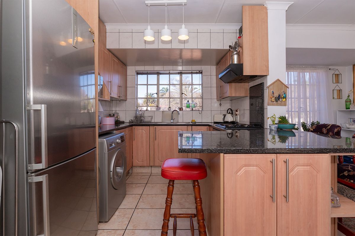 A functional kitchen featuring light wood cabinetry, dark granite countertops, tiled backsplash, and integrated appliance space, offering a practical layout for daily use.