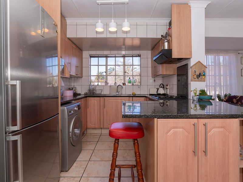 A functional kitchen featuring light wood cabinetry, dark granite countertops, tiled backsplash, and integrated appliance space, offering a practical layout for daily use.