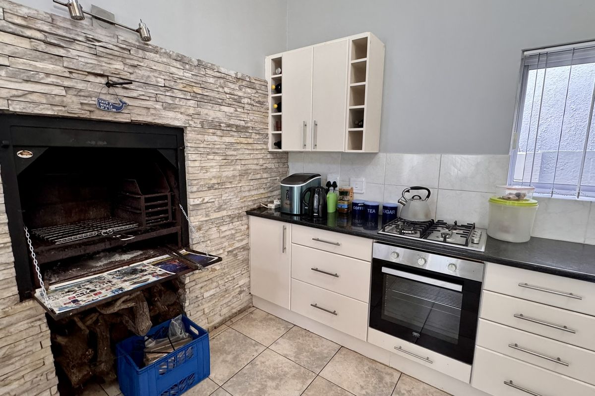 Kitchen area featuring a built-in indoor braai with stone cladding, gas hob, electric oven, and ample built-in cabinetry.