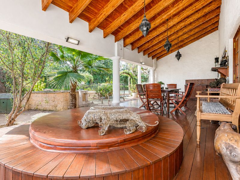 Spacious covered patio featuring timber decking, exposed wooden rafters, and a built-in outdoor entertainment area overlooking the garden.