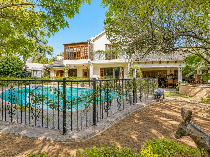 Rear view of the property featuring a swimming pool with wrought iron fencing, a covered patio area, and an upper-level balcony.