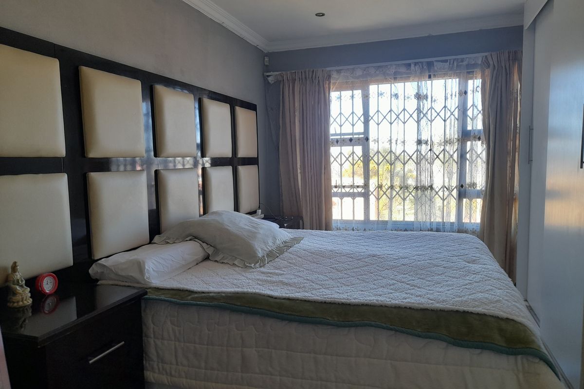 A bedroom featuring a built-in headboard, sliding wardrobe doors, and security bars on the window.