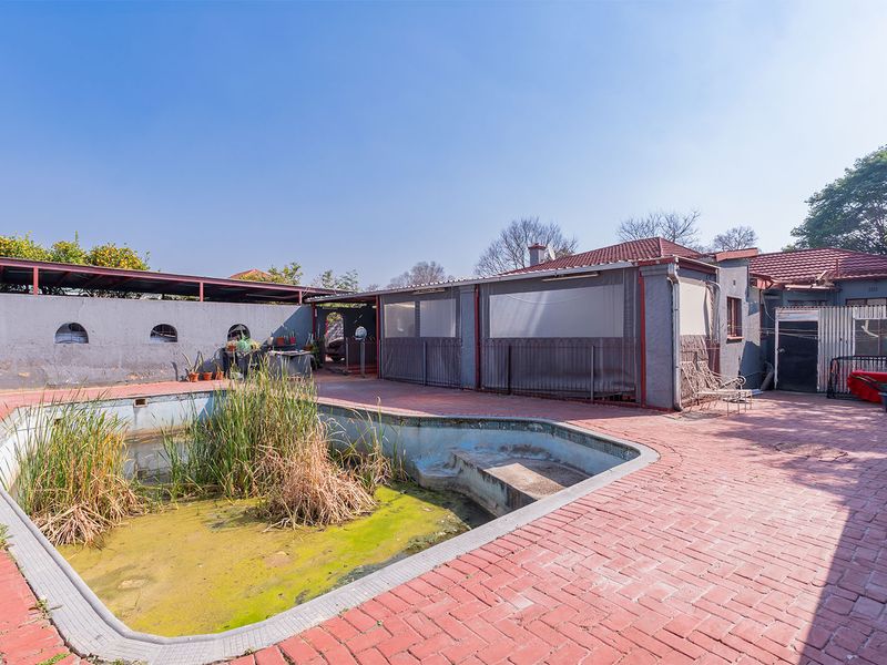 Rear outdoor area featuring a paved patio and a swimming pool in need of significant maintenance and restoration.