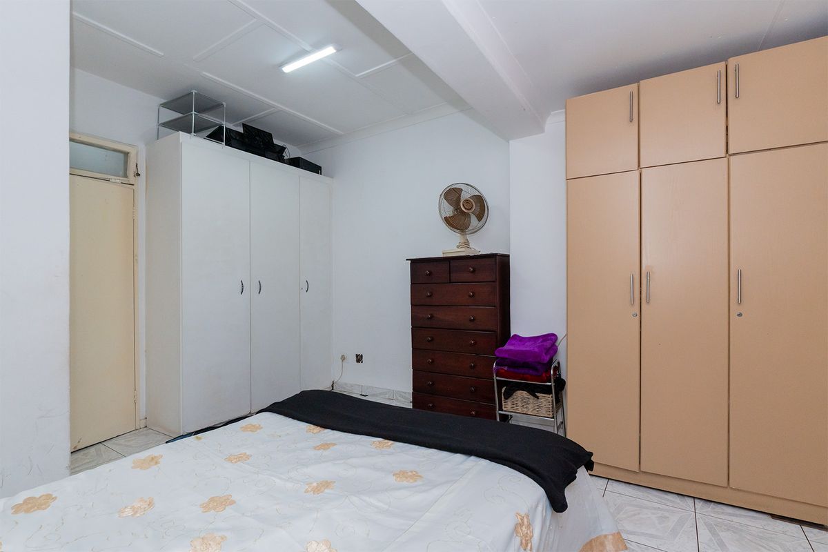 A functional bedroom featuring dual built-in wardrobes, tiled flooring, and neutral wall finishes, offering practical storage space.
