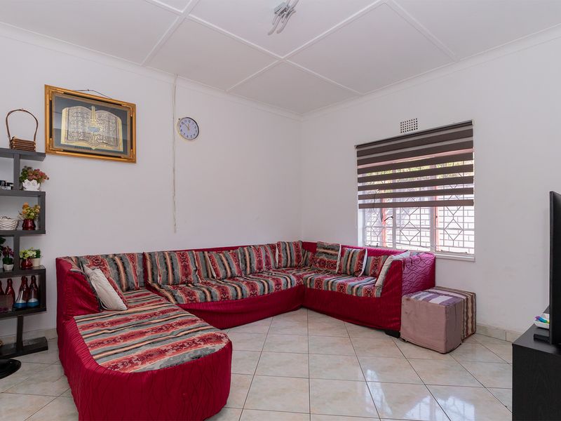 A living room featuring tiled flooring, security bars on the window, and roller blinds, providing a functional and secure living space.