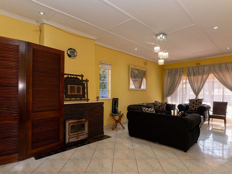 Spacious living room featuring tiled flooring, a built-in fireplace, and a combination of recessed and pendant lighting.