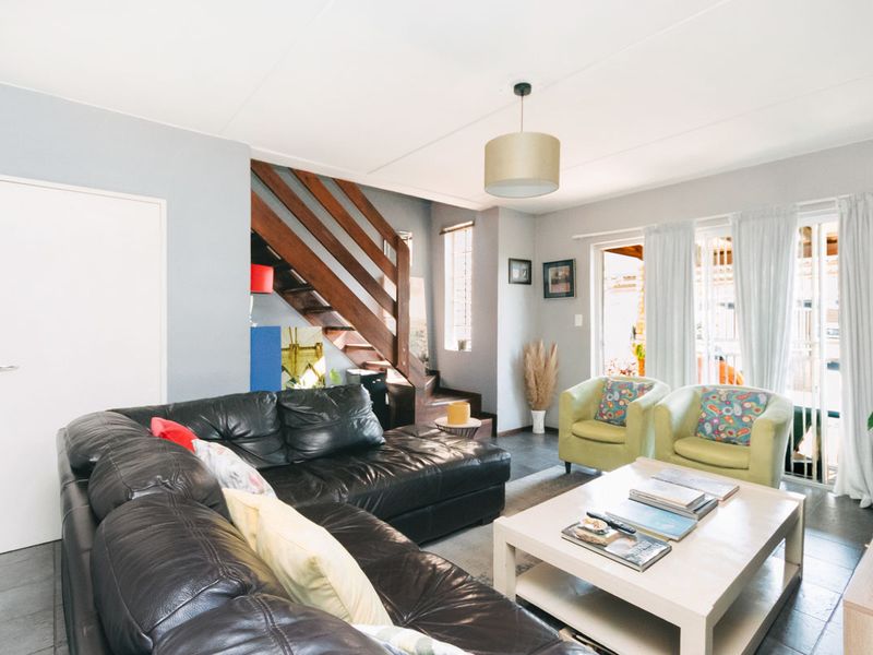 Spacious living room featuring tiled flooring, a wooden staircase, and sliding glass doors providing access to the outdoor area.