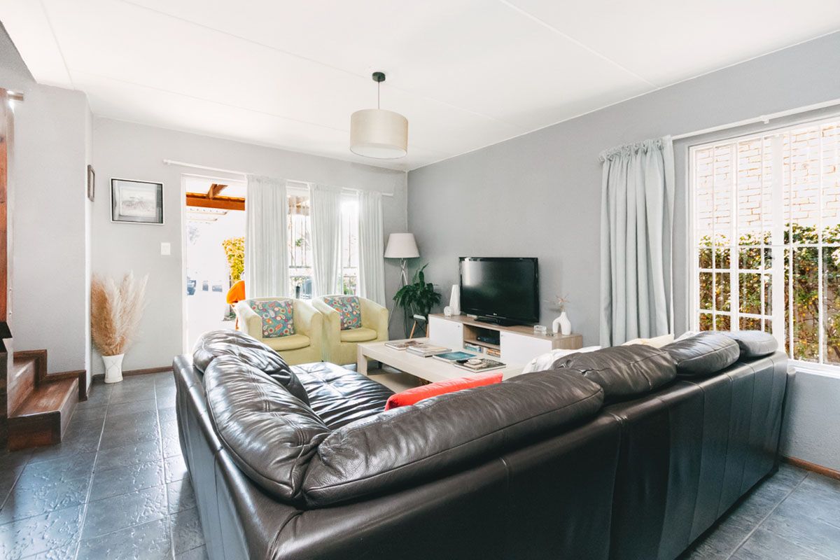 A comfortable living room featuring dark tiled flooring, neutral wall tones, and direct access to an outdoor patio area through a sliding glass door.