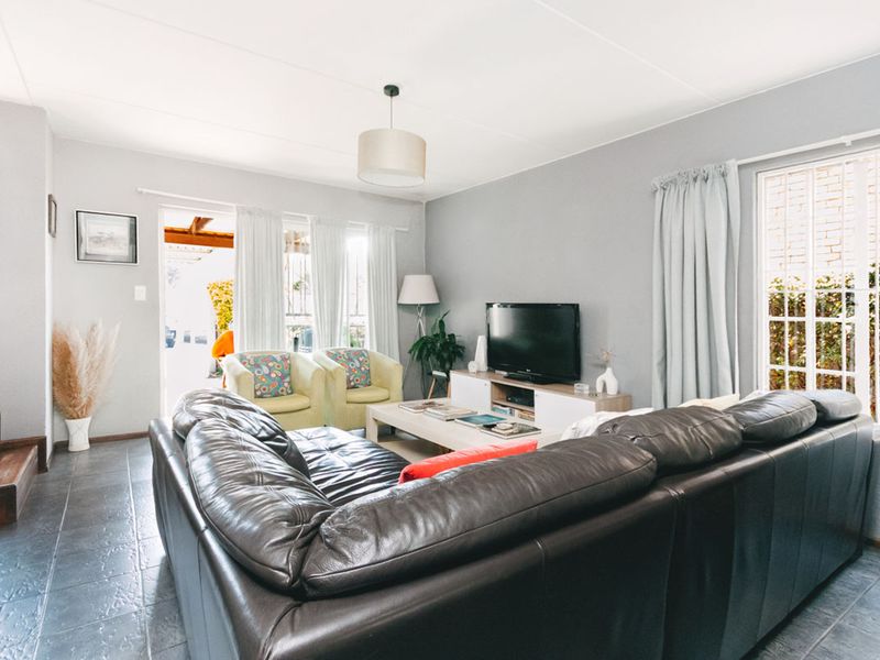 A comfortable living room featuring dark tiled flooring, neutral wall tones, and direct access to an outdoor patio area through a sliding glass door.