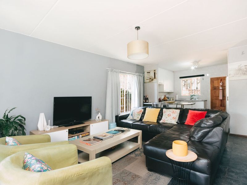 Open-plan living area featuring a combined lounge and kitchen space with tiled flooring and neutral wall finishes.