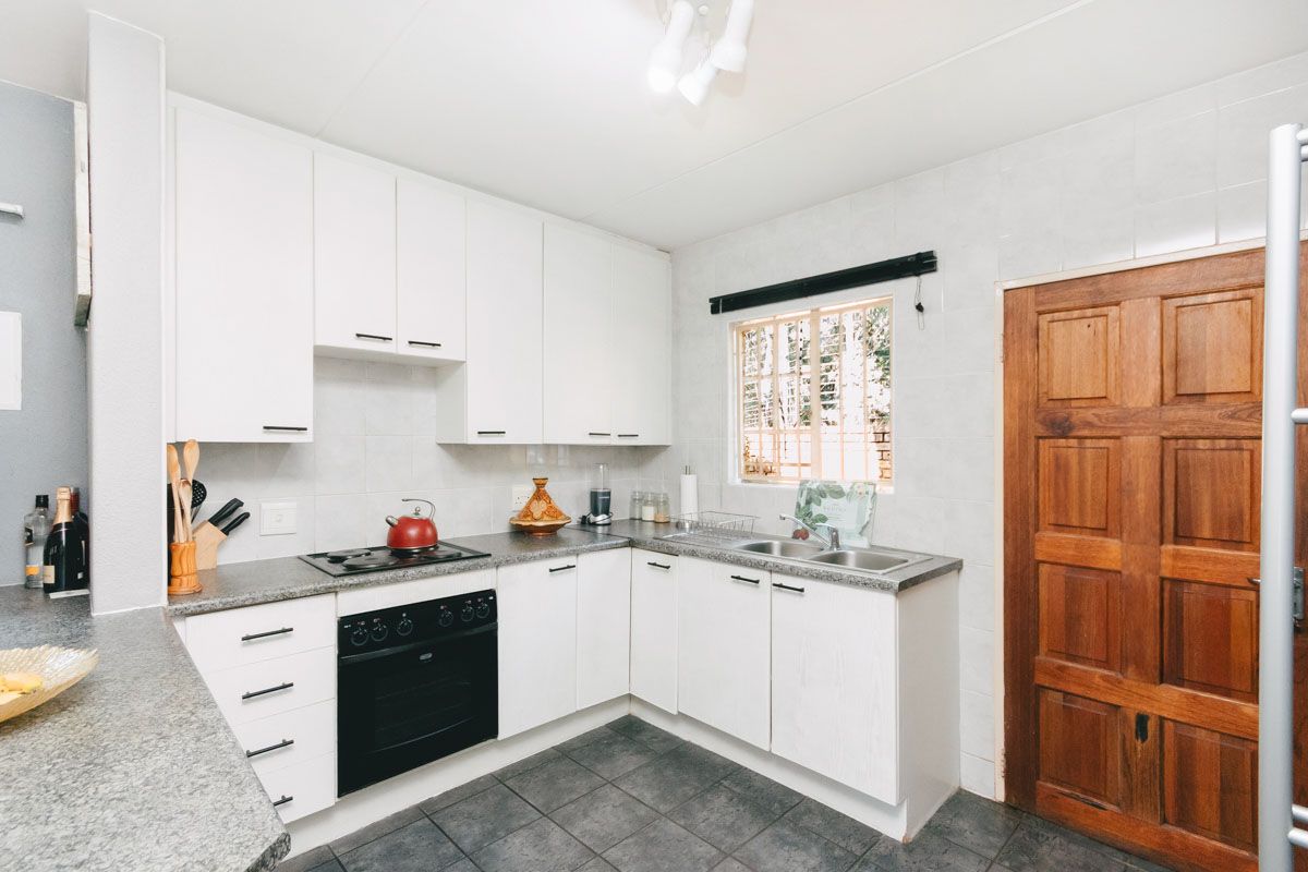 A functional kitchen featuring white cabinetry, granite countertops, a double basin sink, and a built-in oven with an electric hob.