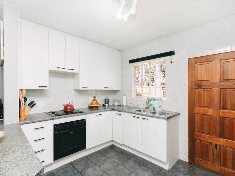A functional kitchen featuring white cabinetry, granite countertops, a double basin sink, and a built-in oven with an electric hob.