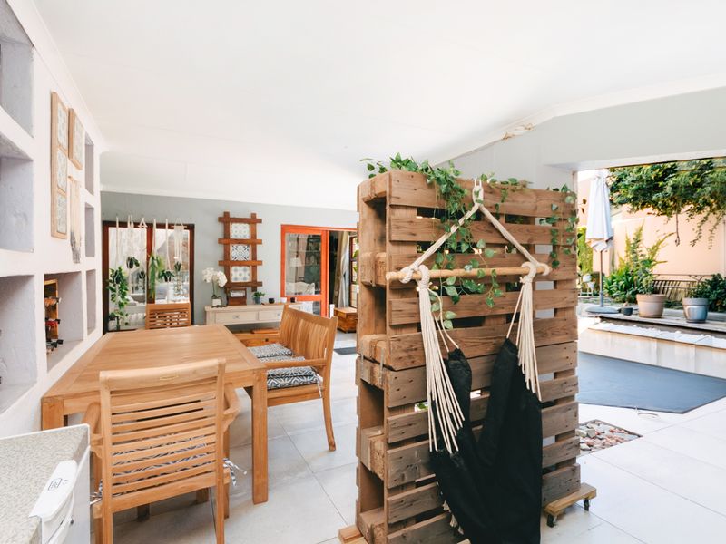 A covered outdoor patio area featuring tiled flooring and built-in wall shelving, providing a seamless transition to the garden and pool area.