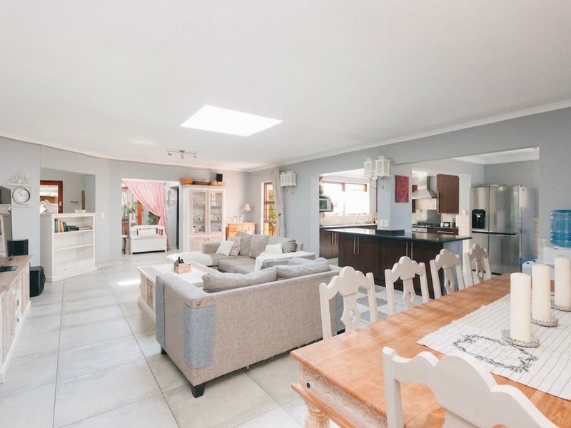Spacious open-plan living and dining area featuring a modern kitchen with a central island, tiled flooring, and a large skylight for natural light.