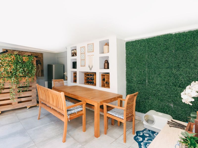 A covered patio area featuring tiled flooring and built-in wall shelving, providing a functional space for outdoor dining and relaxation.