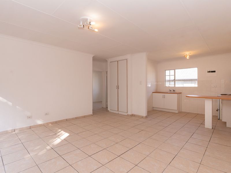 Spacious open-plan living area featuring tiled flooring, a functional kitchen with built-in cabinetry, and a breakfast nook, offering a bright and versatile layout.