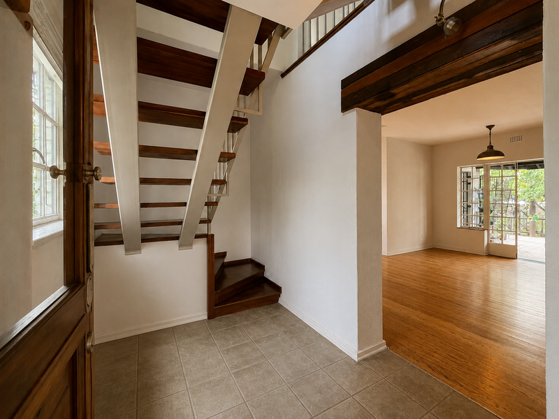 Welcoming entrance hall featuring an open-tread timber staircase, tiled flooring, and a seamless transition into the spacious living area with timber floors.