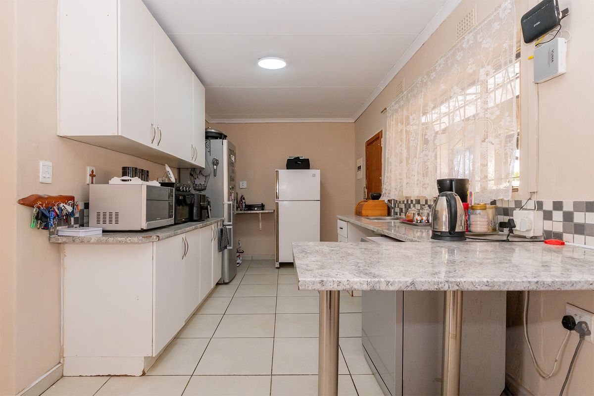 A functional kitchen featuring laminate countertops, tiled flooring, and ample built-in cabinetry with a tiled backsplash.