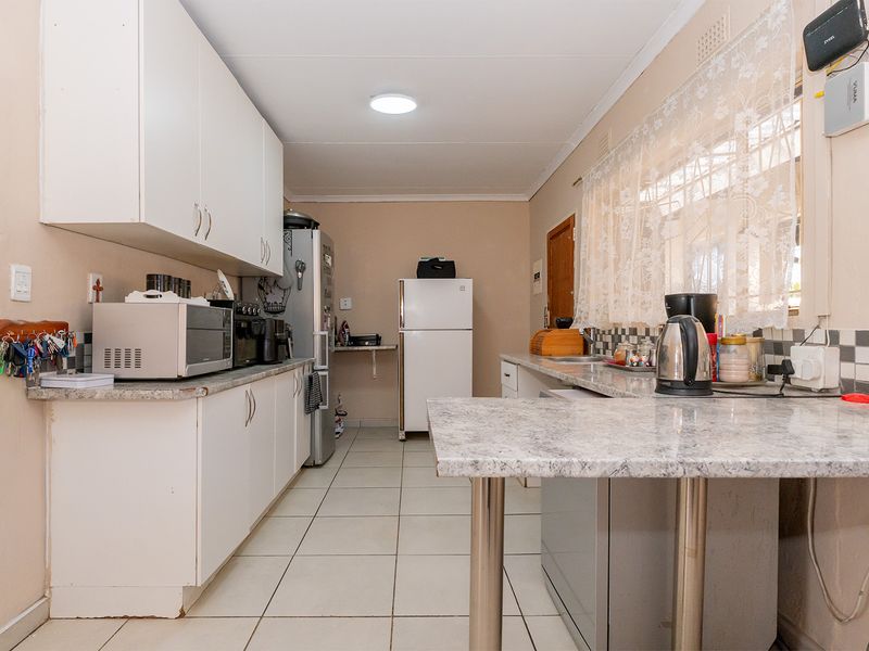 A functional kitchen featuring laminate countertops, tiled flooring, and ample built-in cabinetry with a tiled backsplash.