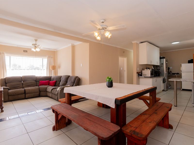 Open-plan living and dining area featuring tiled flooring, ceiling fans, and a functional kitchen with built-in cabinetry and granite countertops.