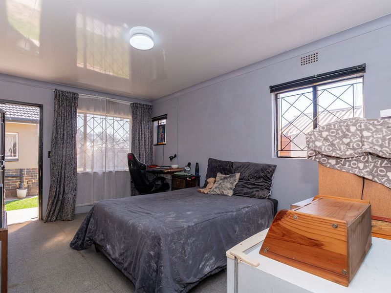 A functional bedroom featuring a glossy ceiling, security gate access to the exterior, and burglar bars on the windows.