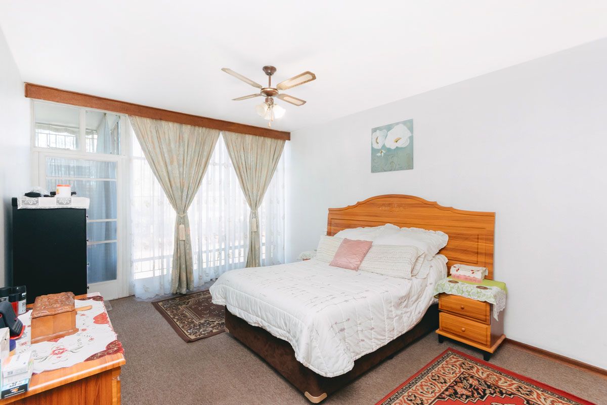 A bedroom featuring carpet flooring, a ceiling fan, and a sliding glass door providing access to an adjacent space.