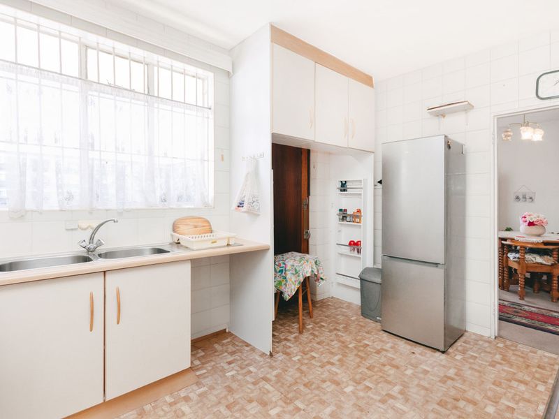 A functional kitchen featuring tiled splashbacks, laminate countertops, a double bowl sink, and built-in cabinetry with ample storage space.