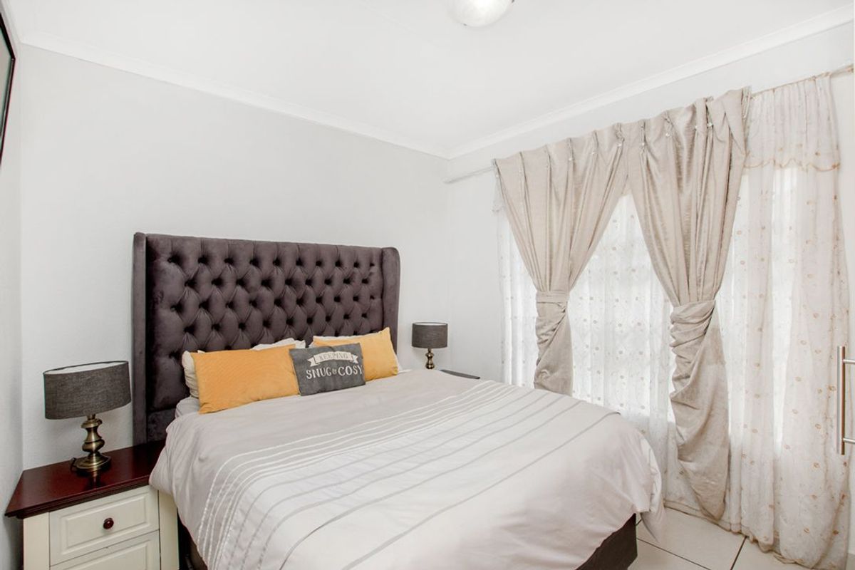 A well-lit bedroom featuring tiled flooring and neutral wall finishes, providing a comfortable and functional sleeping space.