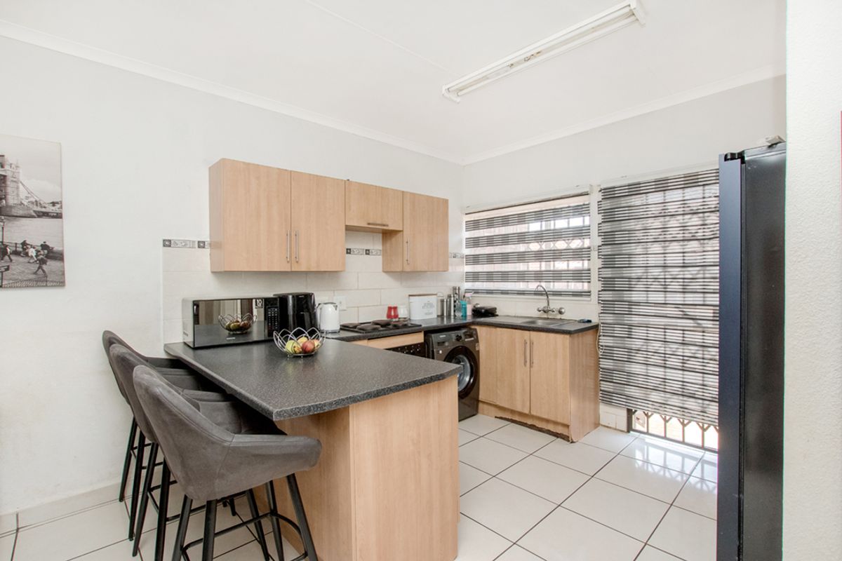 Functional kitchen featuring laminate cabinetry, dark countertops, tiled flooring, and a breakfast bar, providing a practical workspace with integrated sink and cooking area.