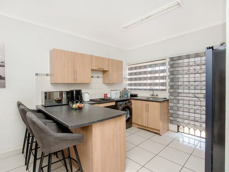 Functional kitchen featuring laminate cabinetry, dark countertops, tiled flooring, and a breakfast bar, providing a practical workspace with integrated sink and cooking area.