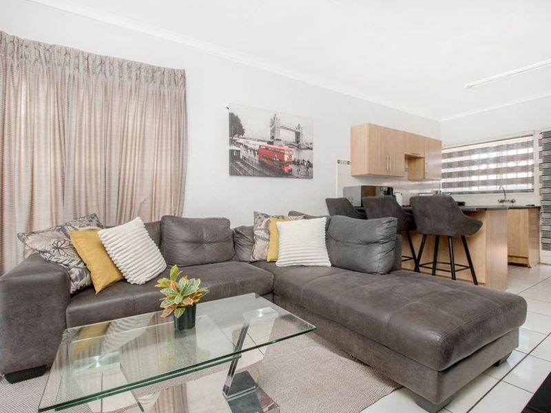 Open-plan living area featuring a kitchen with built-in cabinetry and island, flowing into a lounge space with tiled flooring.