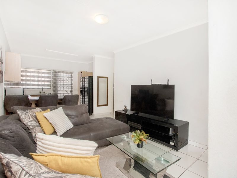 Open plan living area featuring tiled flooring and a connected kitchen space with a breakfast bar, providing a functional layout for daily living.