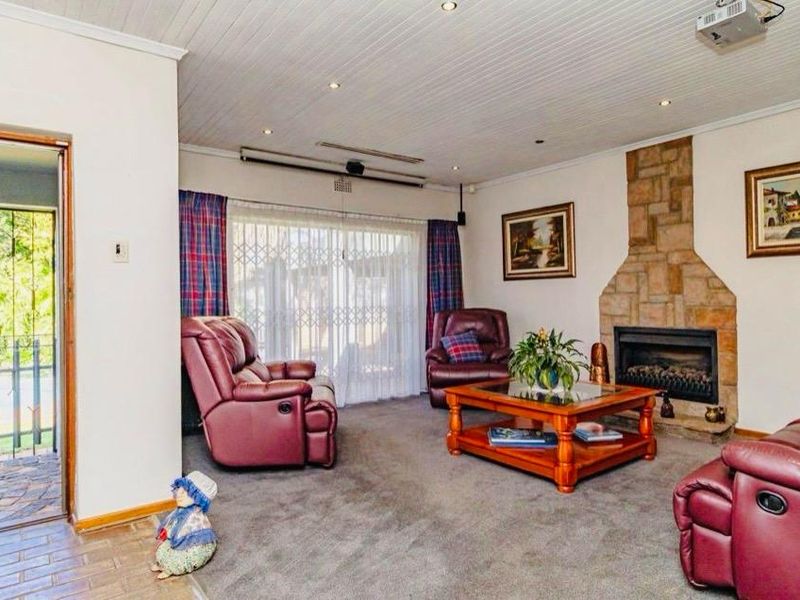 A spacious living room featuring a stone fireplace, recessed lighting, and direct access to the outdoor pool area through a sliding glass door.