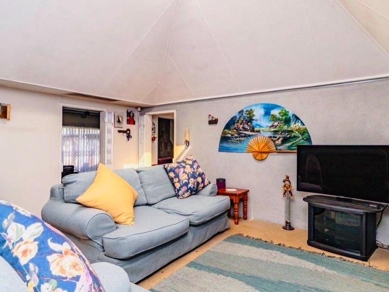 A living room featuring a vaulted ceiling and access to adjacent spaces, providing a comfortable and functional area for relaxation.