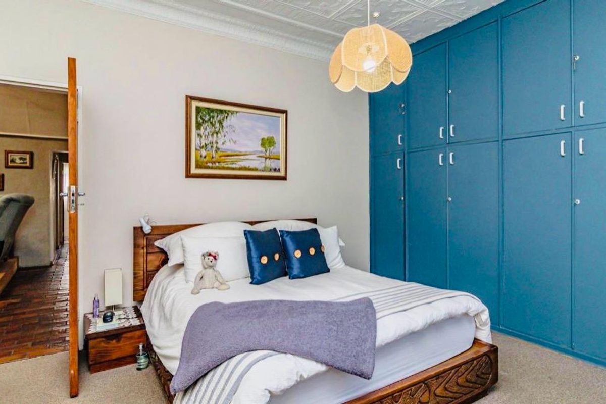 A well-maintained bedroom featuring extensive floor-to-ceiling blue built-in cupboards and a decorative ceiling finish.